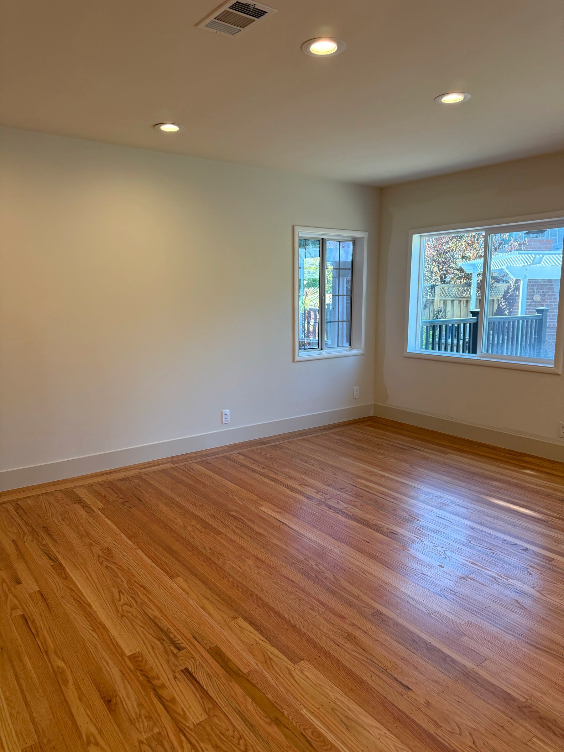 Empty bright room with newly refinished oak floors, cleaned after construction