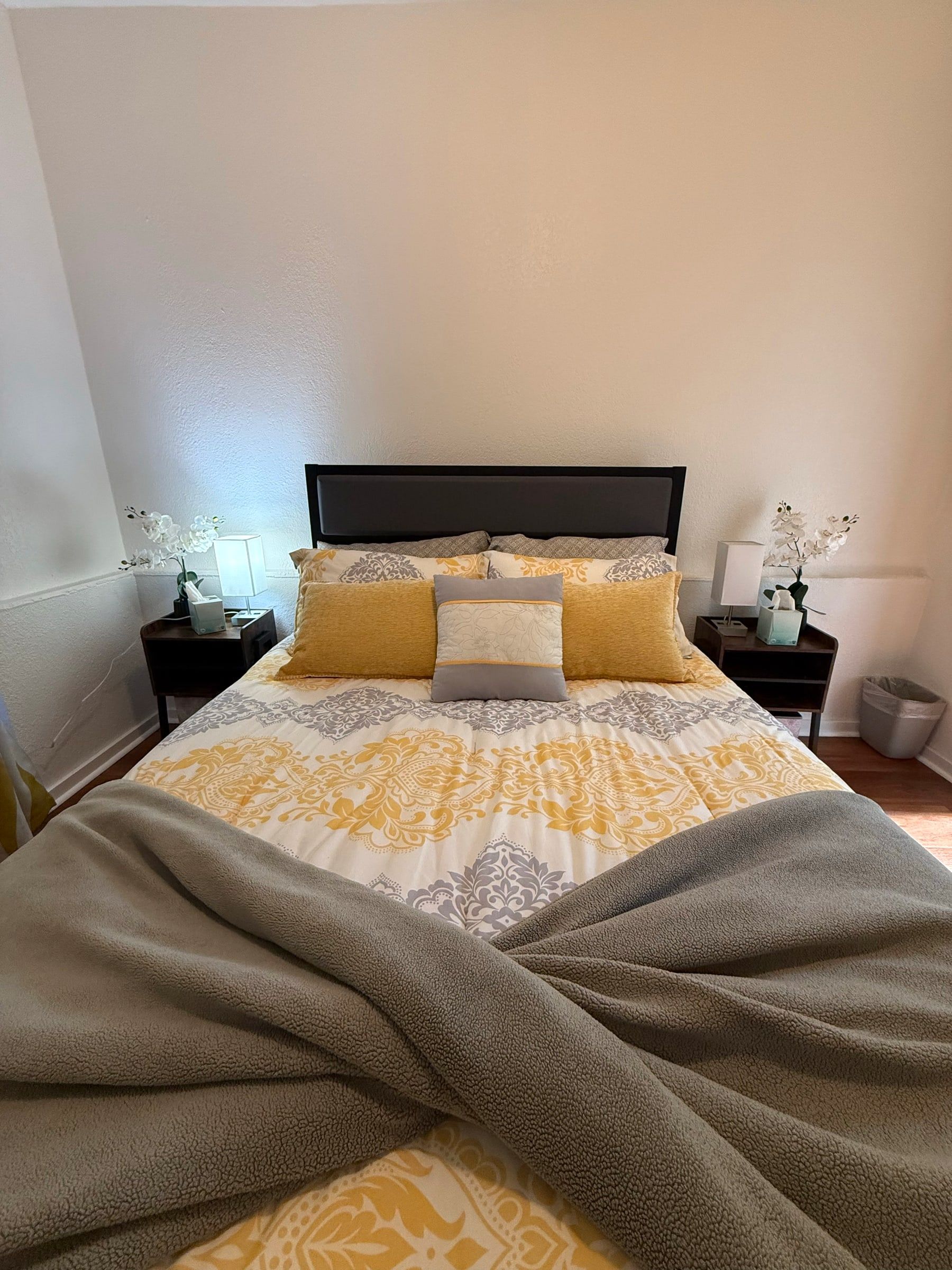Neatly made bed with yellow bedding and a folded throw